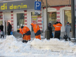 Рабочие в яркой оранжевой спецодежде убирают снег на проезжую часть
